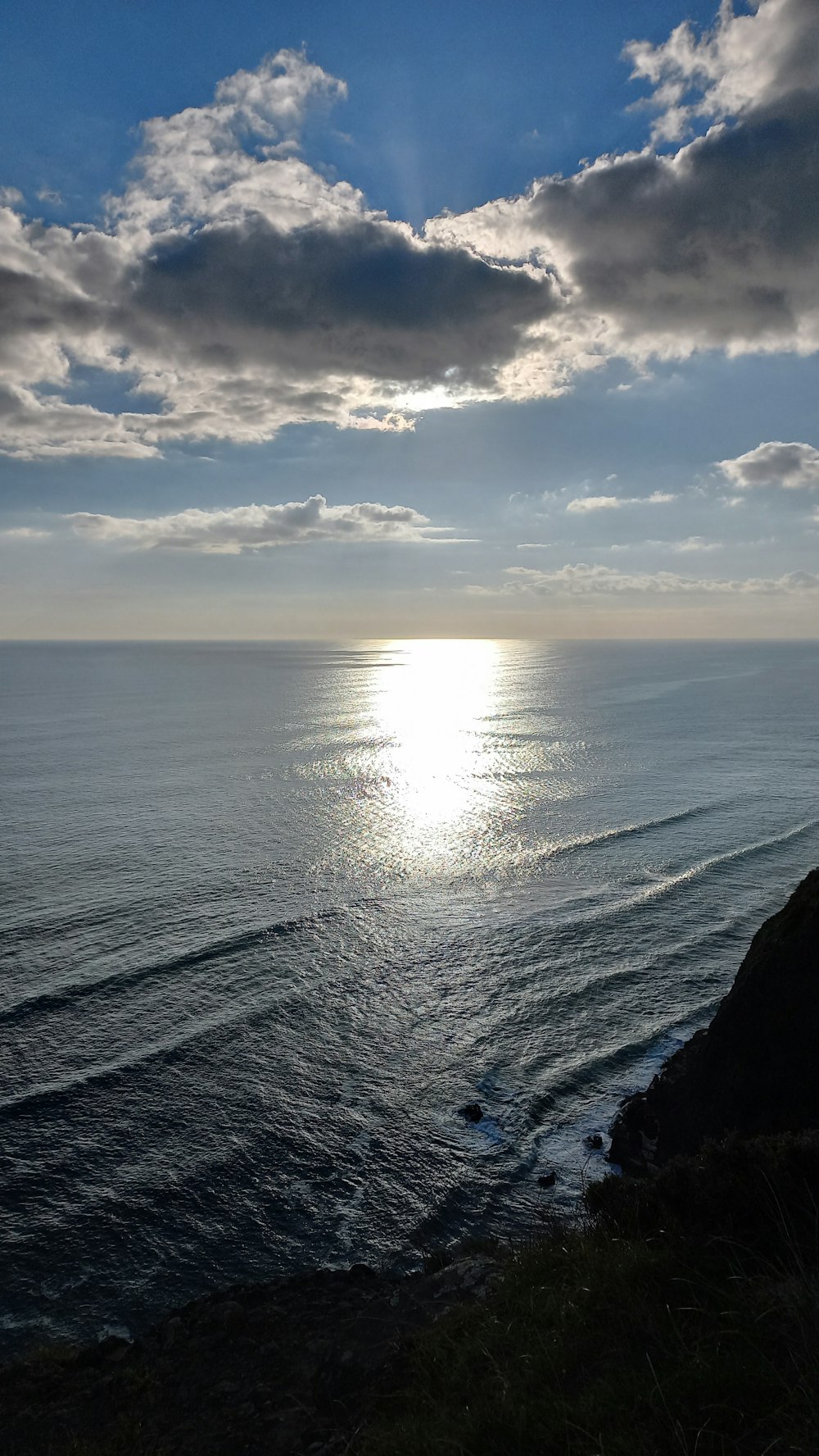 a body of water with a beach and clouds in the sky