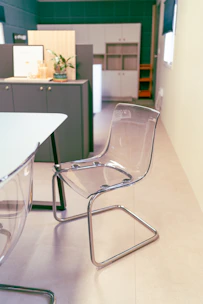 A clear acrylic back dining chair placed beside a minimalist wooden table.