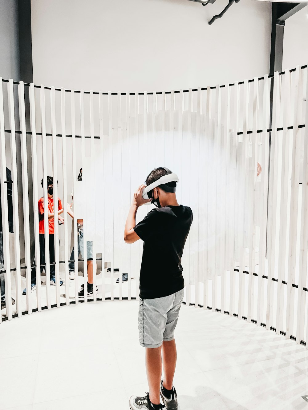 a person wearing a hat and headphones standing in front of a white fence