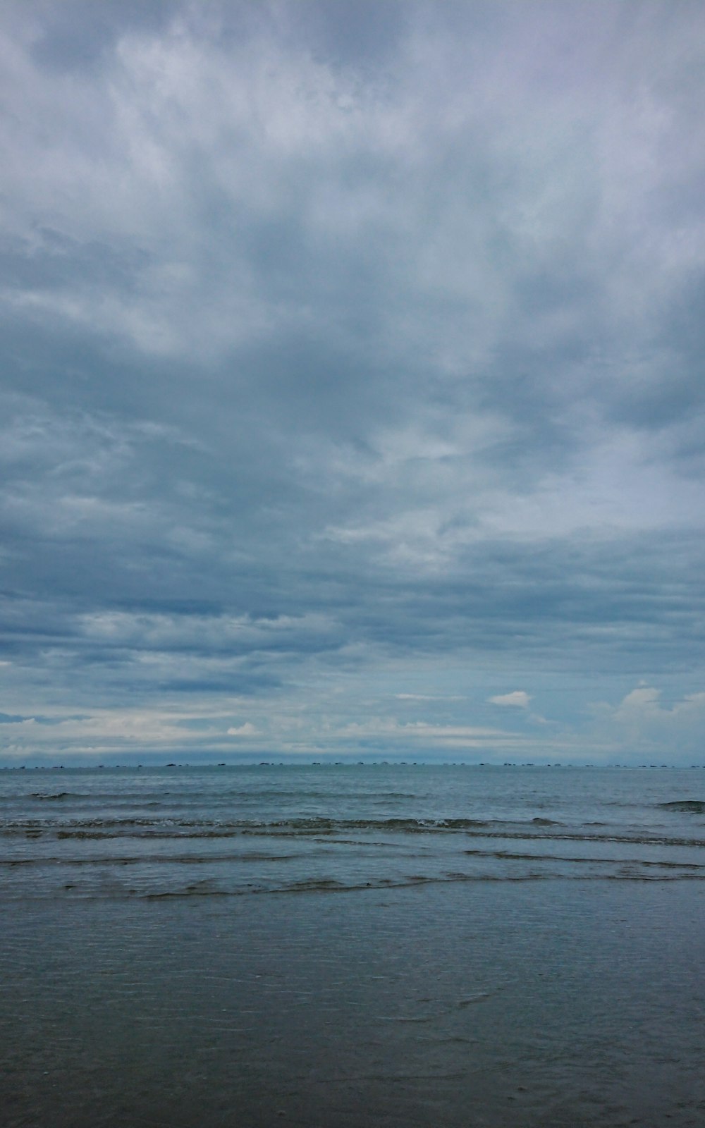 a beach with waves and clouds