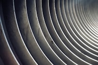 A series of parallel, concentric metal rings creating a tunnel-like effect, with light and shadows playing along the curves.