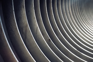 A series of parallel, concentric metal rings creating a tunnel-like effect, with light and shadows playing along the curves.
