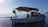 A small boat is floating on calm water, with a clear blue sky above. The boat has a canopy providing shade to a person seated inside, engaged in an activity, possibly fishing or repairing equipment. Various tools and items are scattered around the deck, indicating it is a working vessel.