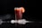 Close-up of a chilled glass filled with a vibrant fruit drink on a dark surface.