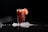 Close-up of a chilled glass filled with a vibrant fruit drink on a dark surface.