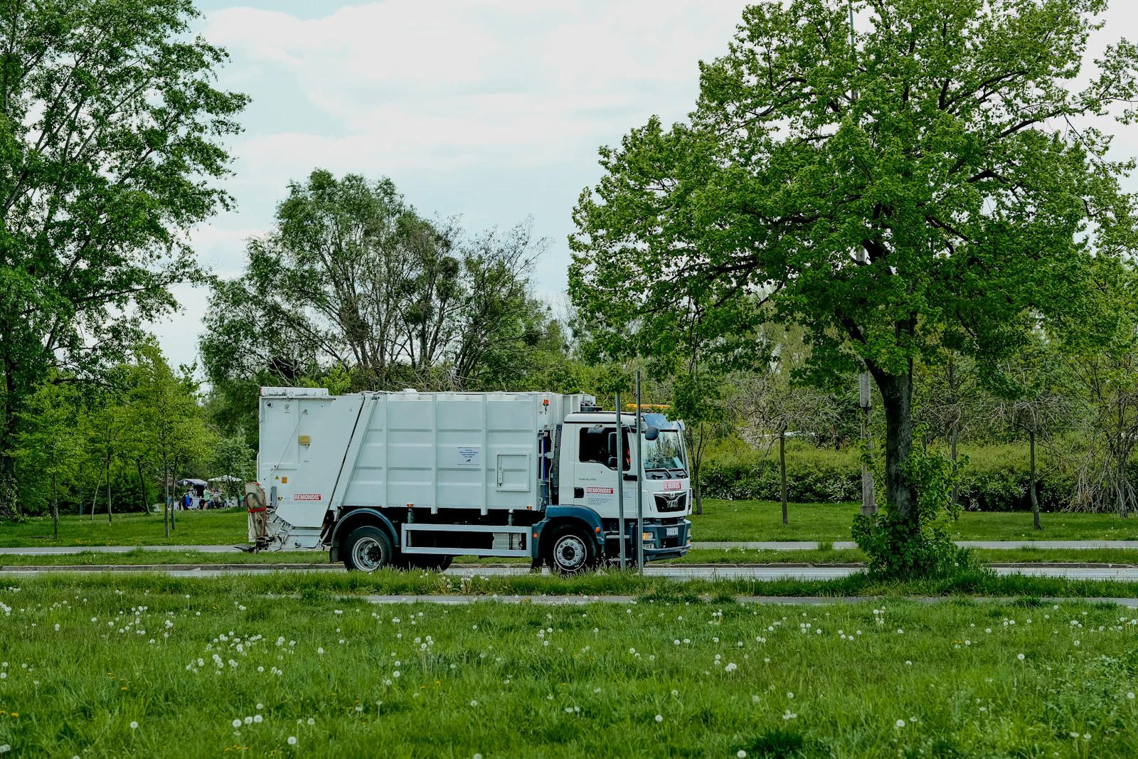 A heavy truck parked beside trees on open ground