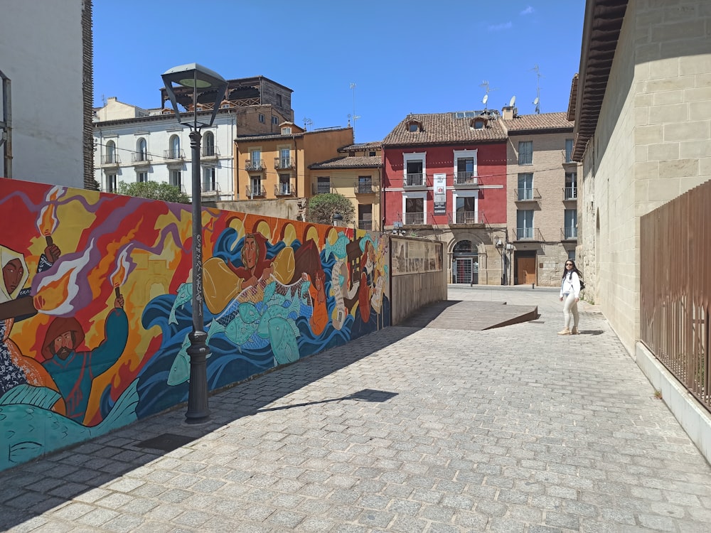 a person walking on a street with graffiti on the side