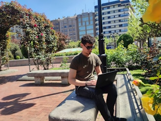 a man sitting on a bench with a laptop
