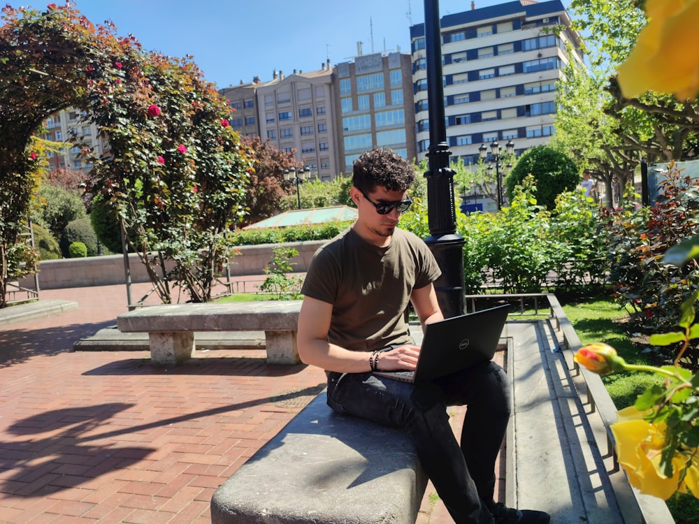 a man sitting on a bench with a laptop