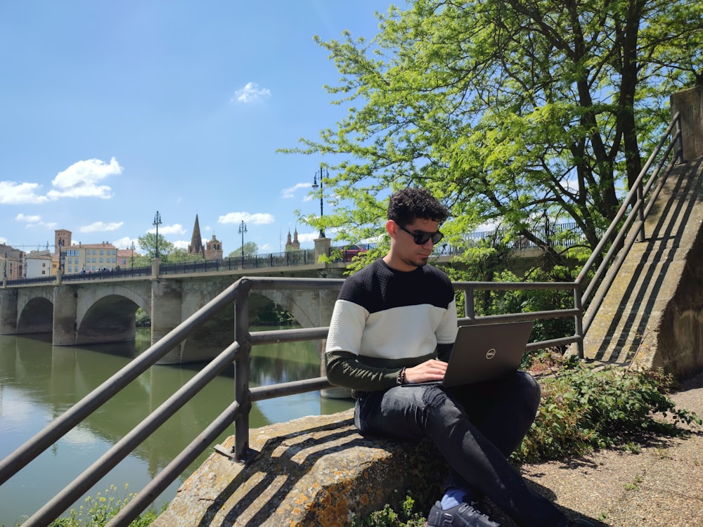 a man sitting on a bench with a laptop