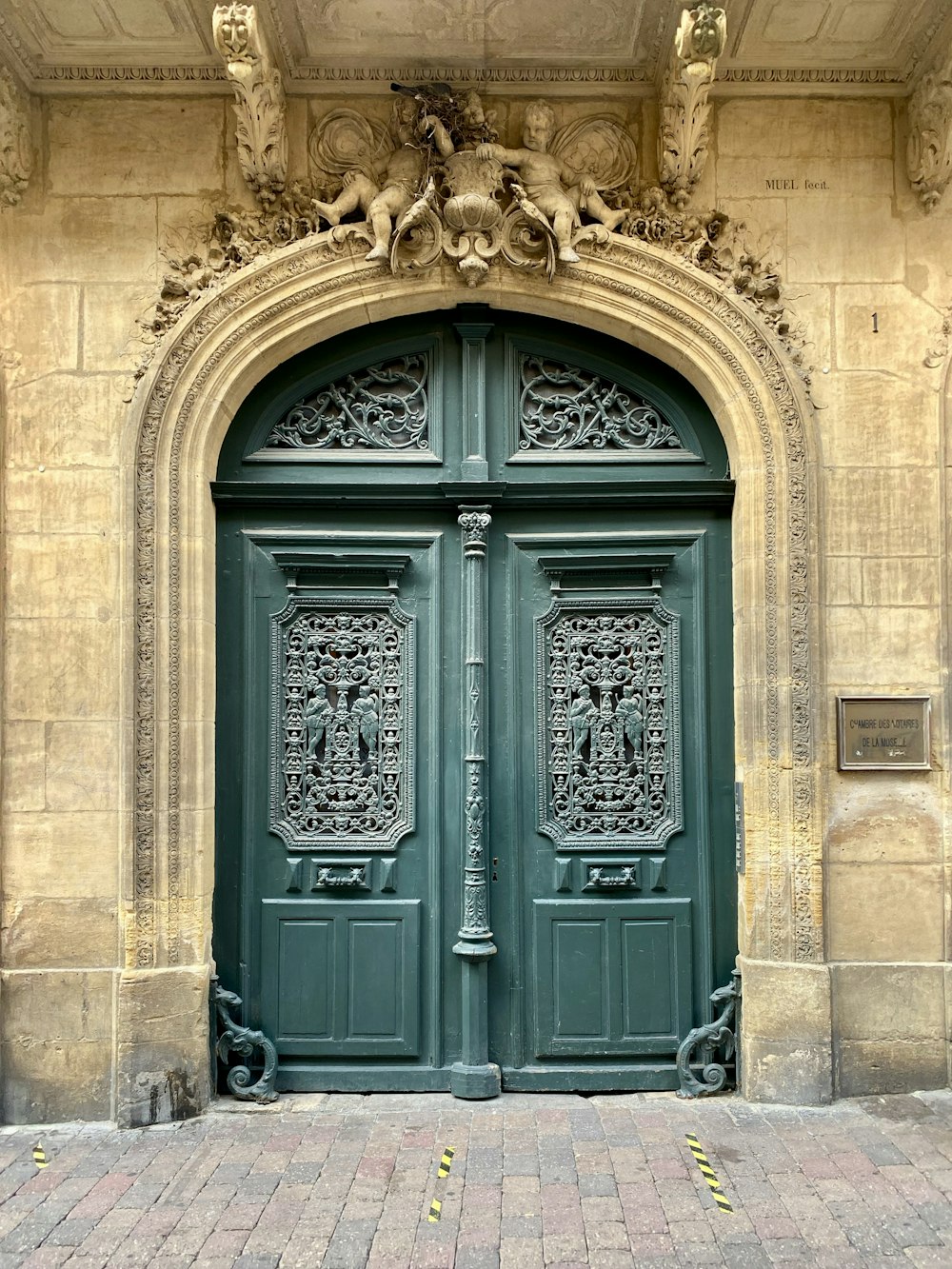 a green door with a statue on top of it