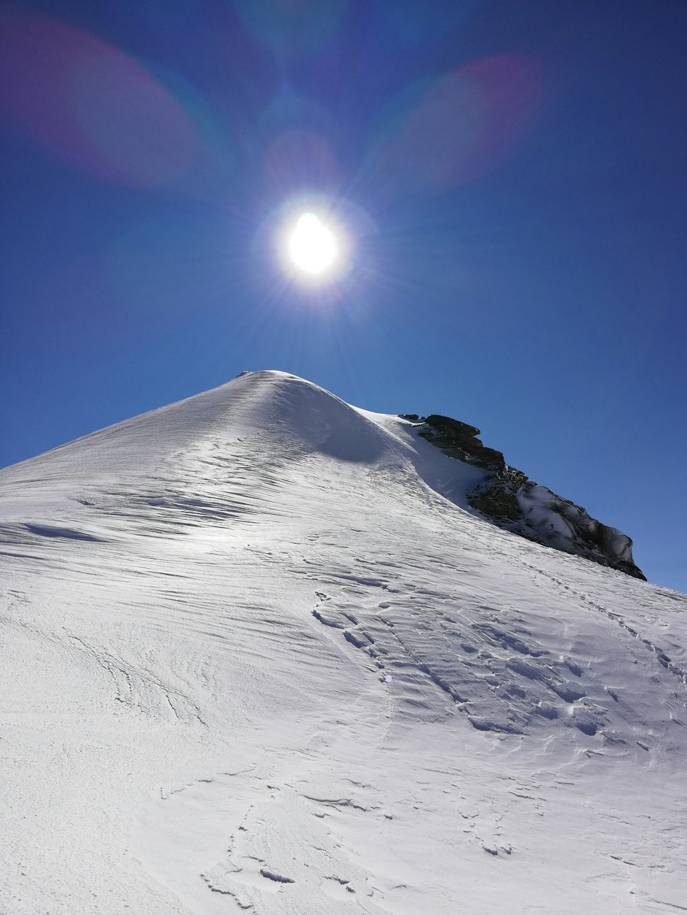 a snowy mountain with the sun in the background