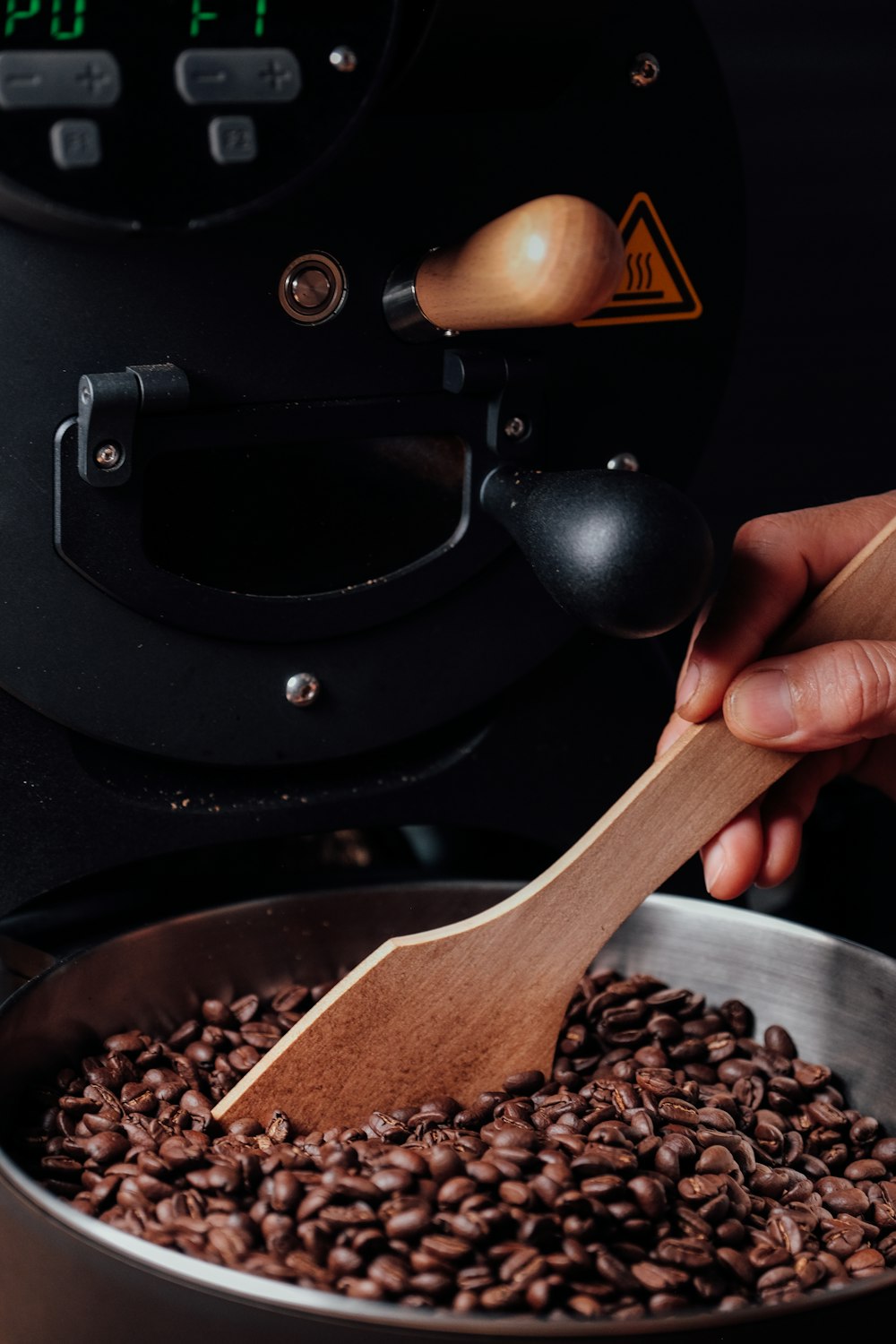 a hand holding a wooden spoon over a bowl of beans