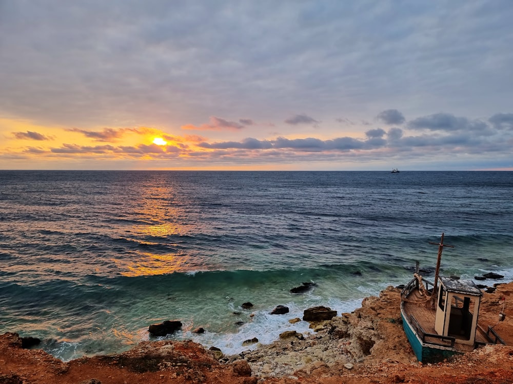 a beach with a chair and a body of water with a sunset