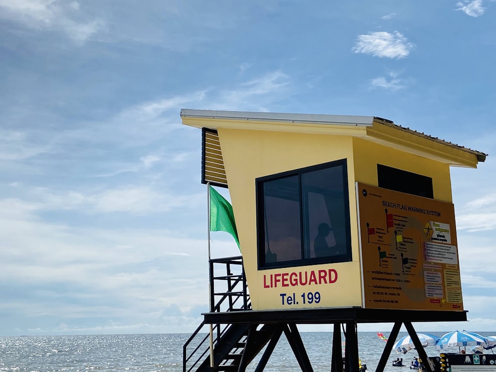 a yellow and white building with a flag on it by the water