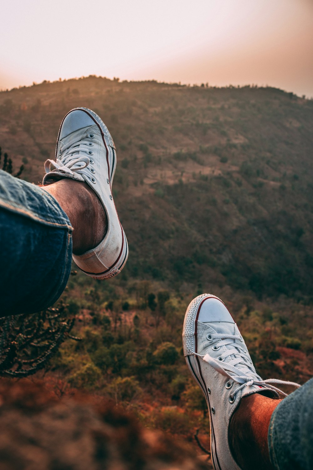 a person's feet on a rock overlooking a forest