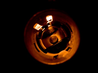 A close-up view of the interior of a cylindrical object, possibly a socket or light fixture, illuminated with a warm orange glow. Circular components and metallic elements are visible within the cylindrical structure.