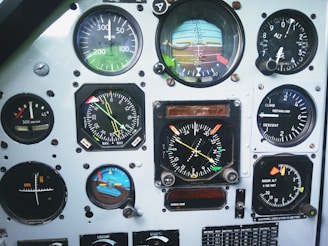 A collection of various analog gauges and dials from an aircraft instrument panel. The instruments include an airspeed indicator in knots, an altimeter, a vertical speed indicator, a compass, and an artificial horizon. Each gauge has distinct markings, needles, and some have colored flags.