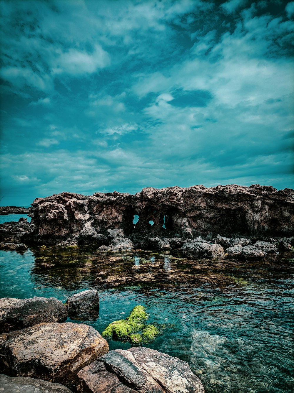 a rocky cliff with a body of water below