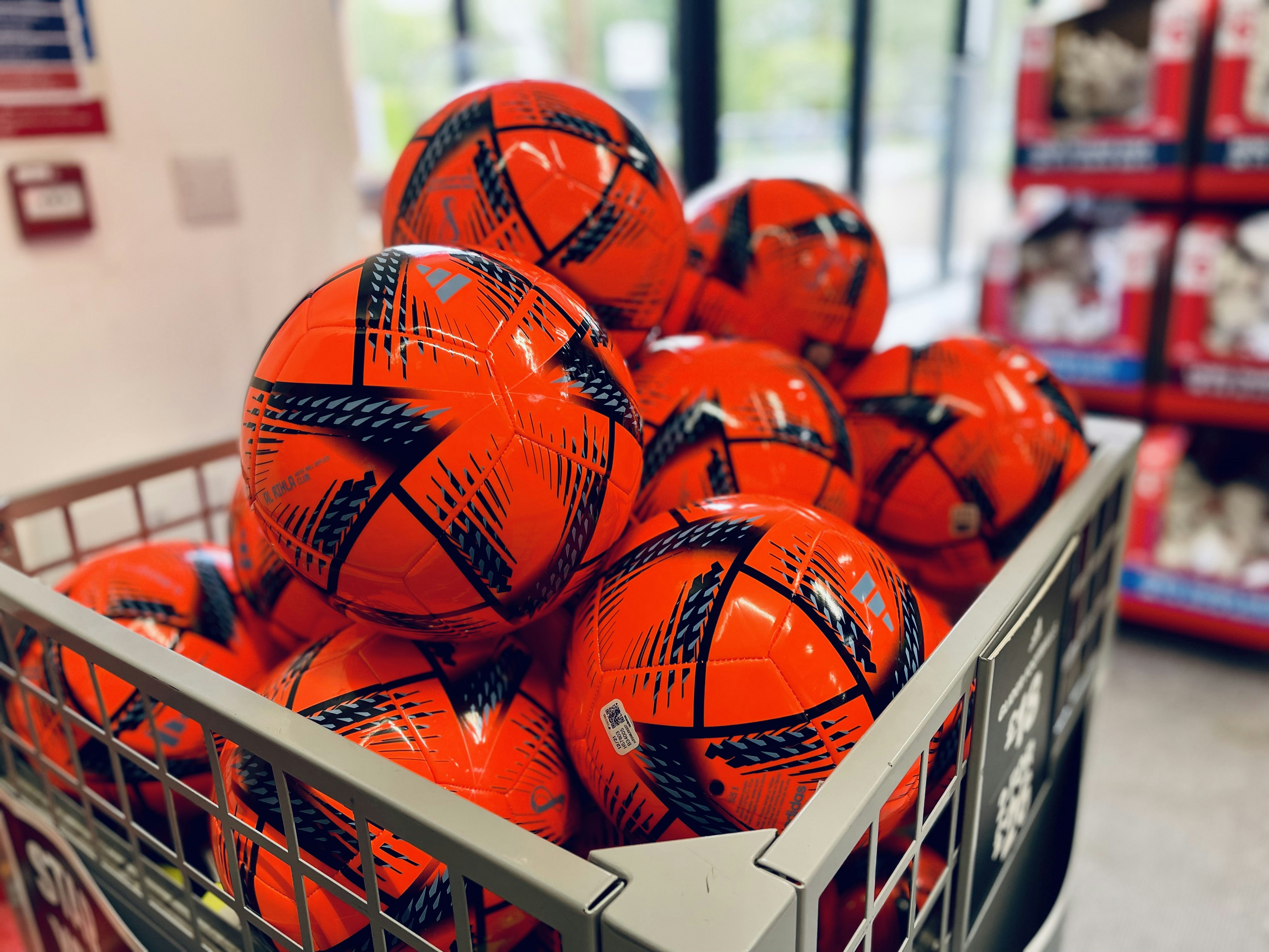 Sturdy metal ball holder showcasing various ball sizes in a sports store setting.