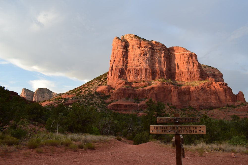 a sign in front of a rock formation with Bell Rock in the background