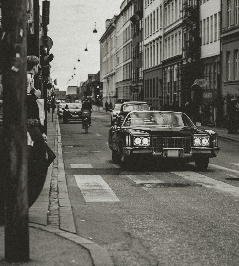 a black and white photo of a car on a street with buildings
