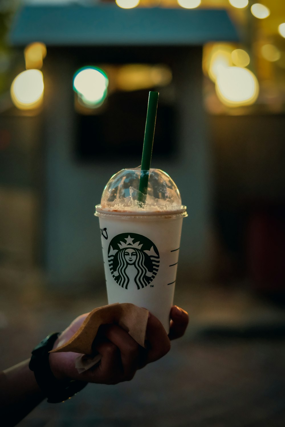 a hand holding a plastic cup with a straw