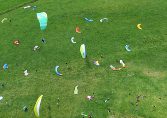 A group of excited flyers preparing their gear beside colorful paragliders.
