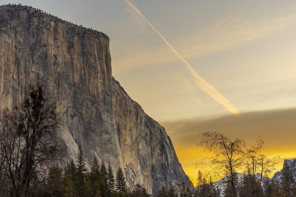 a mountain with trees and a trail of smoke