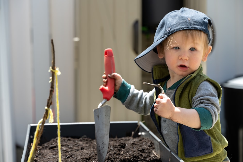 a young boy holding a red shovel