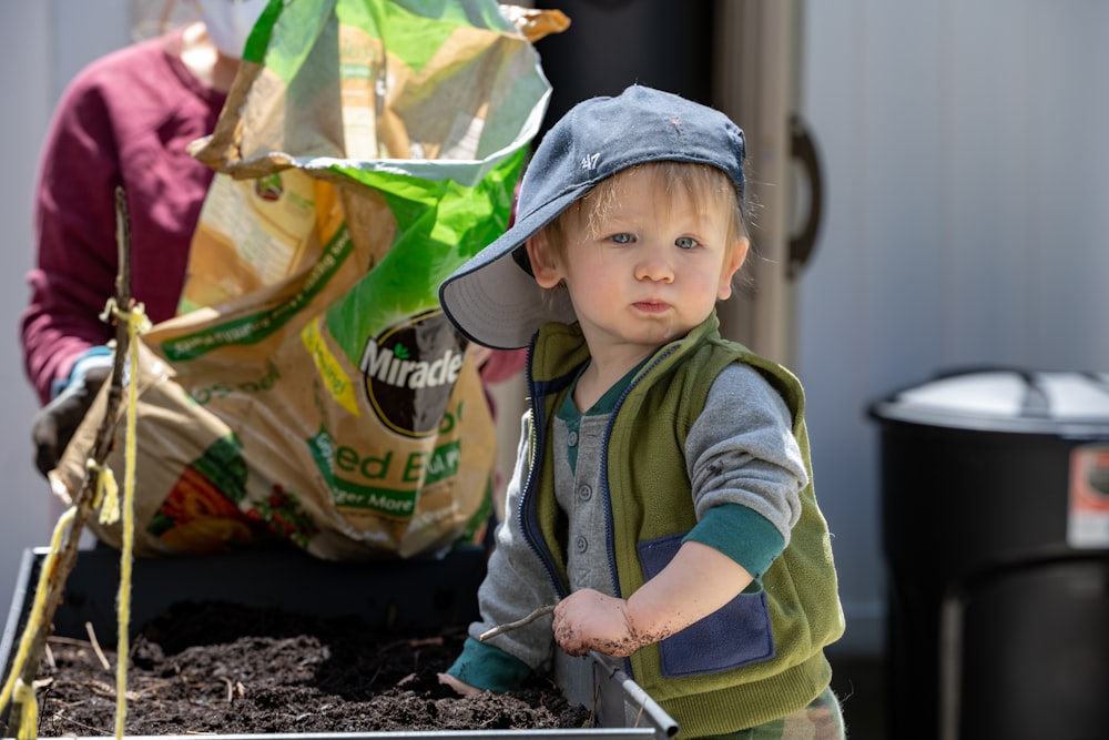 a baby standing next to a bag