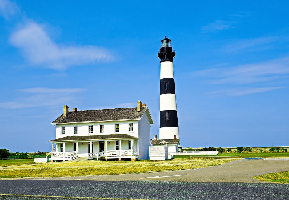 a lighthouse next to a house with Bodie Island Lighthouse in the background