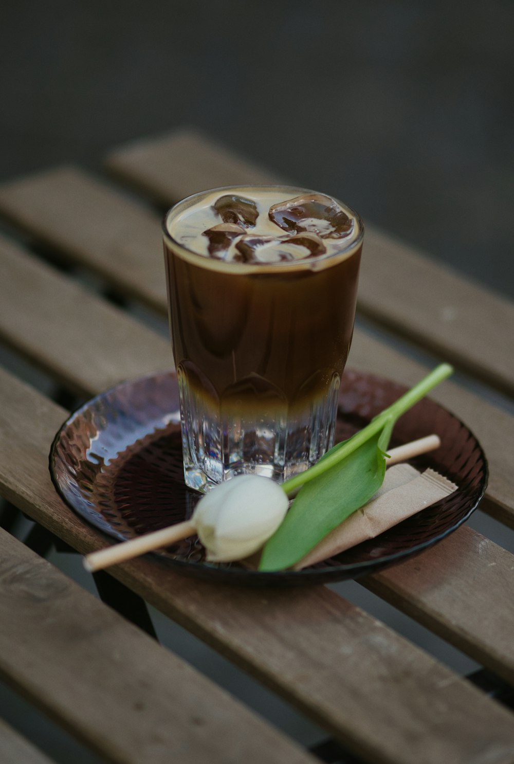 a glass of beer and a plate of sliced limes on a wood table