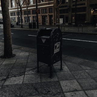 Close-up of a perfectly aligned mailbox post with fresh concrete footing and a USPS-compliant black mailbox, taken during golden hour.