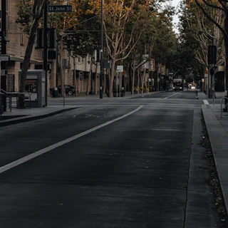 A quiet urban street at dawn, empty except for footprints leading into the distance.
