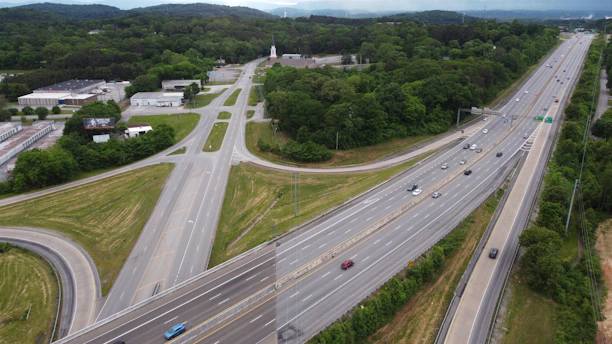 Aerial view of a busy highway interchange surrounded by green landscape.