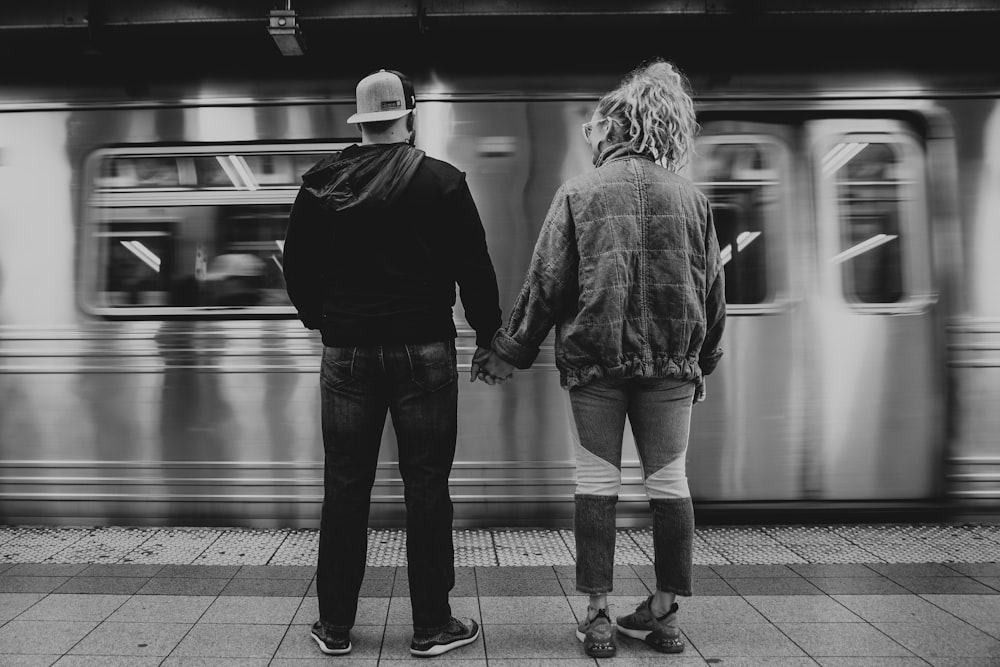 a couple of people stand near a train