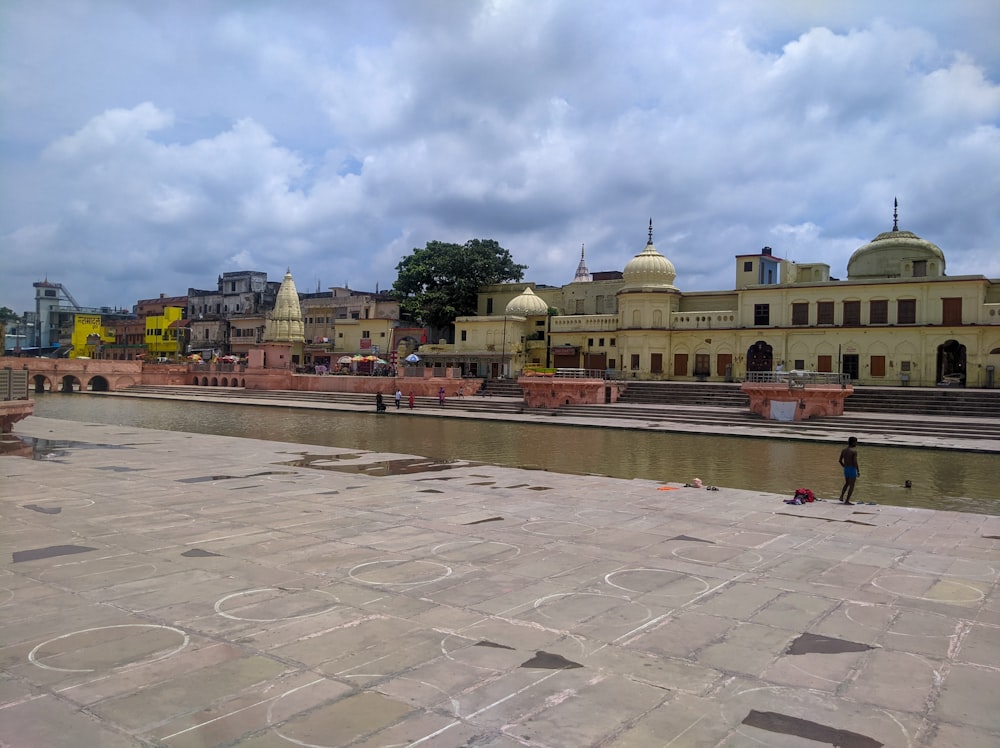 a large courtyard with a body of water and buildings in the background