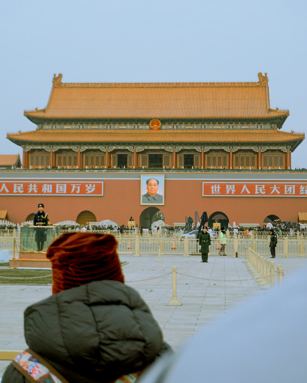 a person sitting on a bench in front of a building with a large red roof