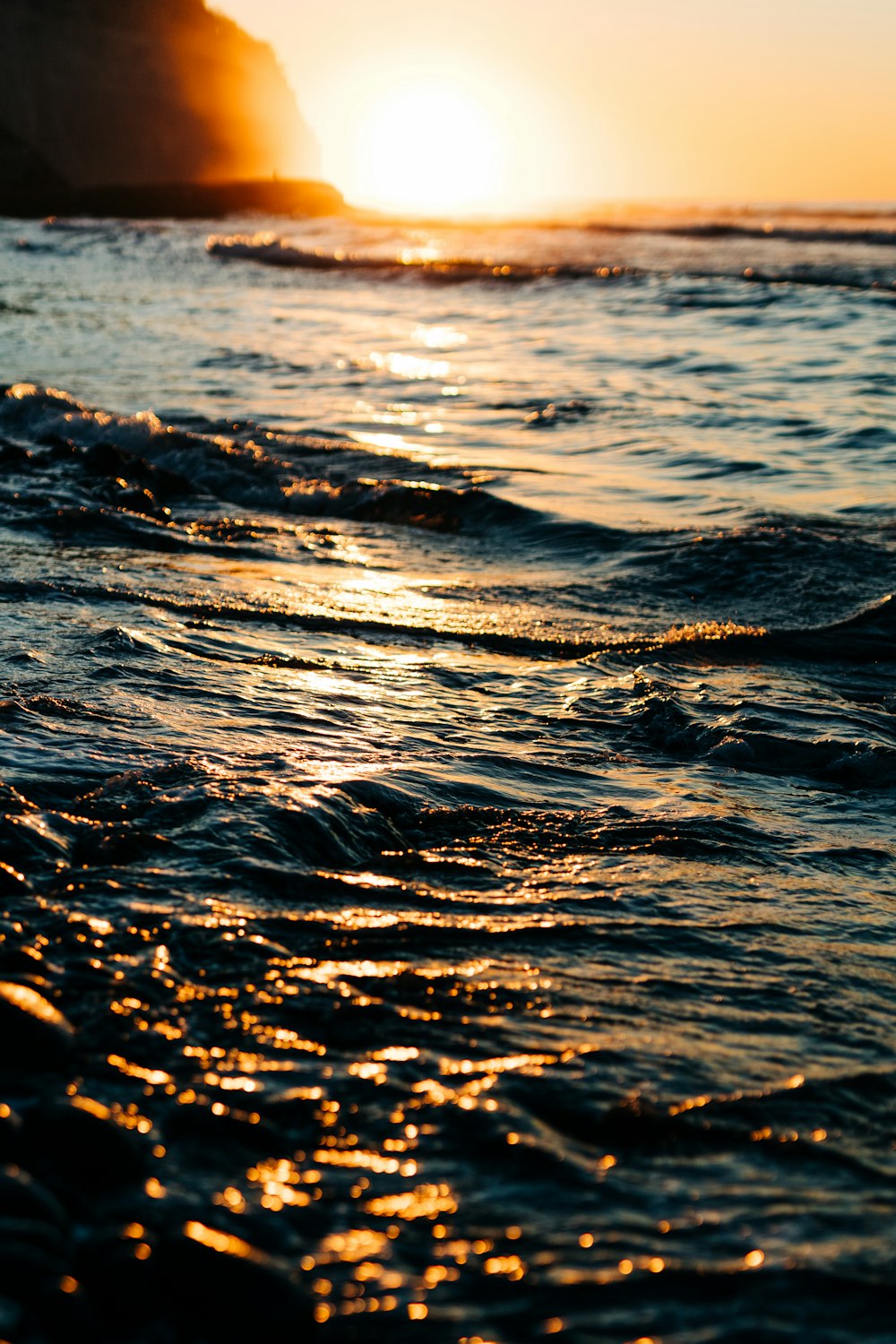 un plan d’eau avec des vagues et un coucher de soleil