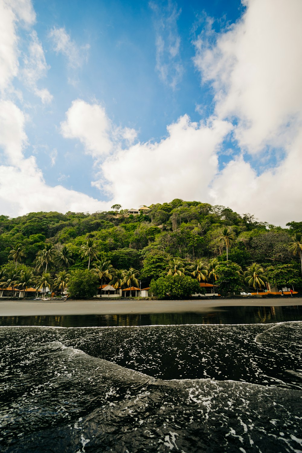 a body of water with trees and a hill in the background