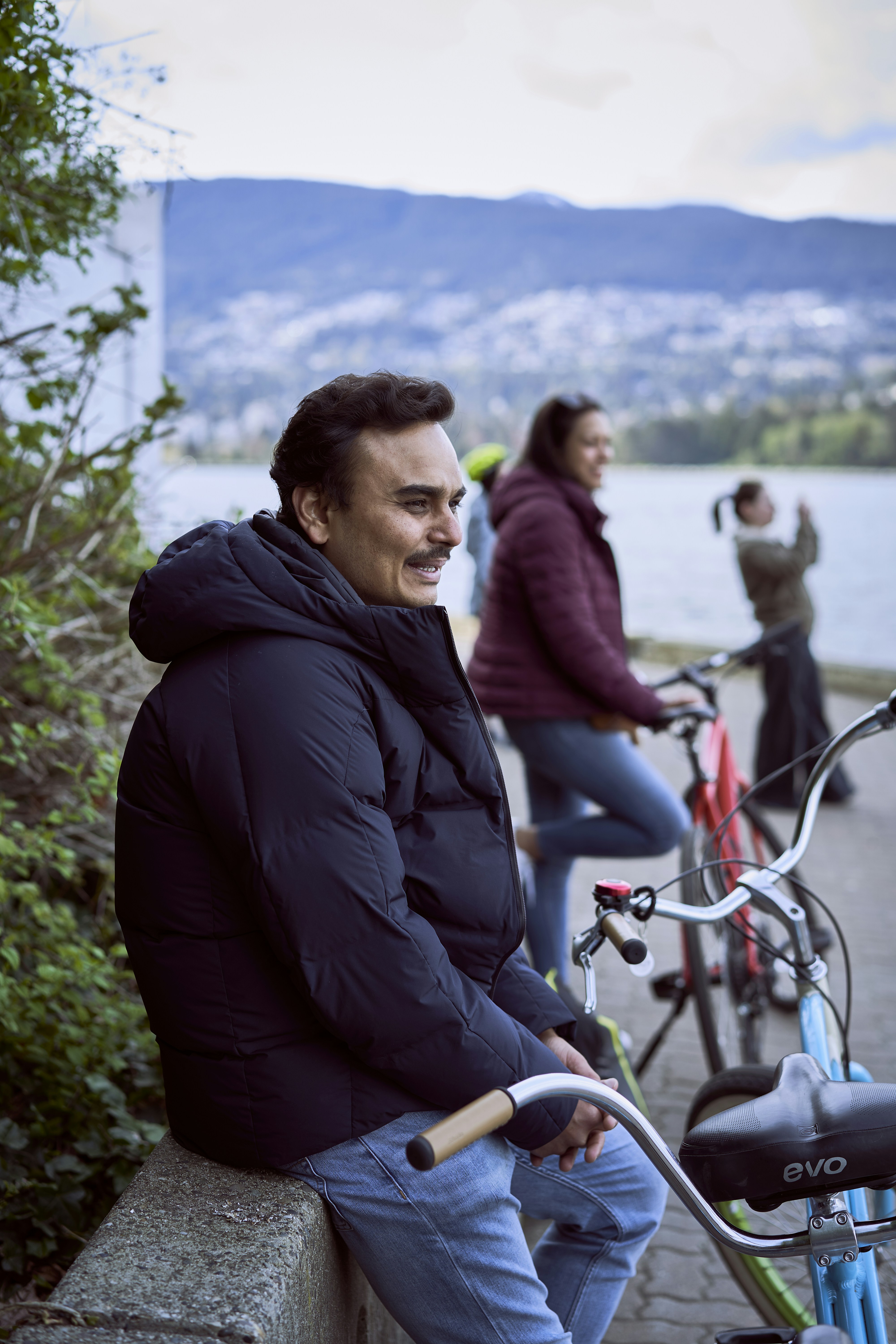 a man sitting on a bench with a bicycle and a woman standing behind him