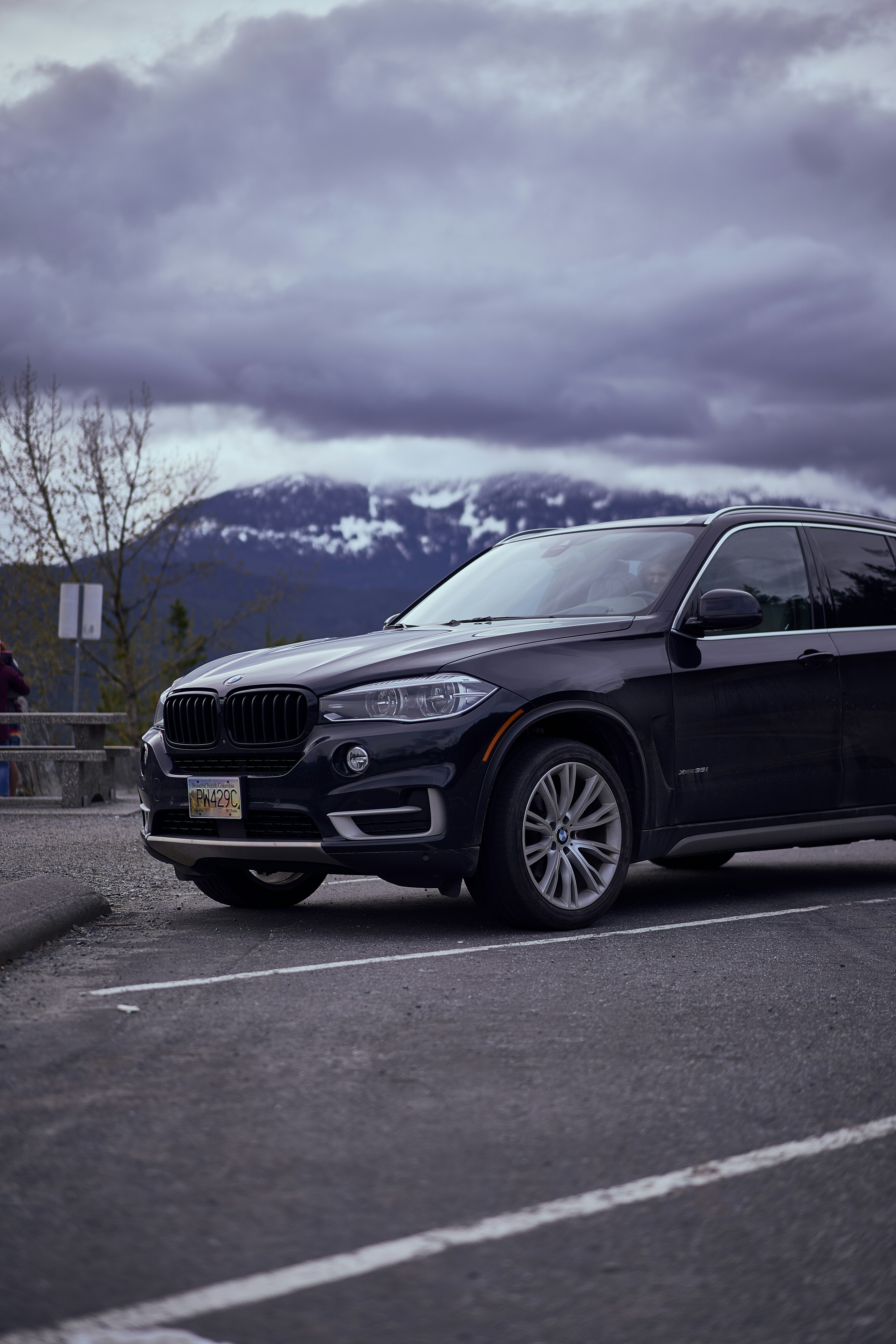 a black car parked in a parking lot with mountains in the background