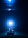A small vehicle with wheels is positioned underwater, tethered to a glowing light source. The scene is bathed in a deep blue hue, creating an ethereal and mysterious ambiance.