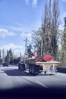 Heavy industrial machinery being transported on a flatbed truck along a coastal highway.