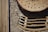 An intricate design featuring a variety of natural materials, including a cross-section of a tree trunk with drilled holes, surrounded by bundles of hollow bamboo tubes. Horizontal wooden slats add structural complexity, showcasing a blend of textures and circular patterns.