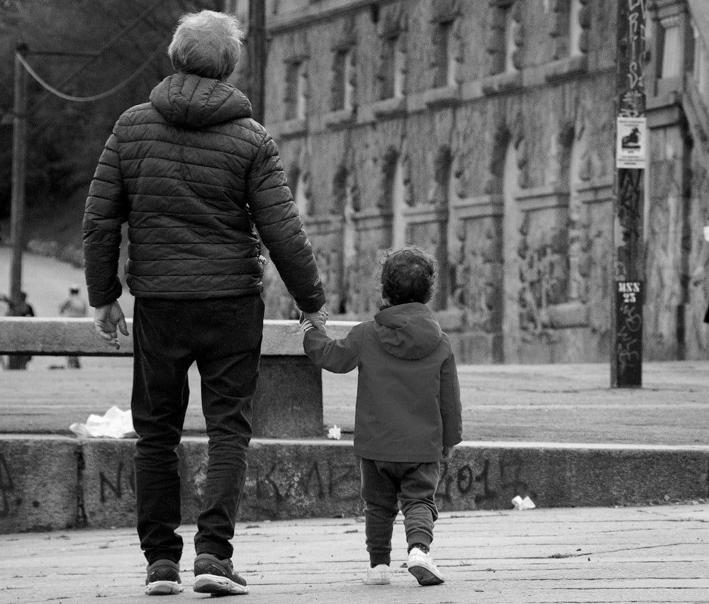 eine Person und ein Kind, die auf einem Bürgersteig gehen