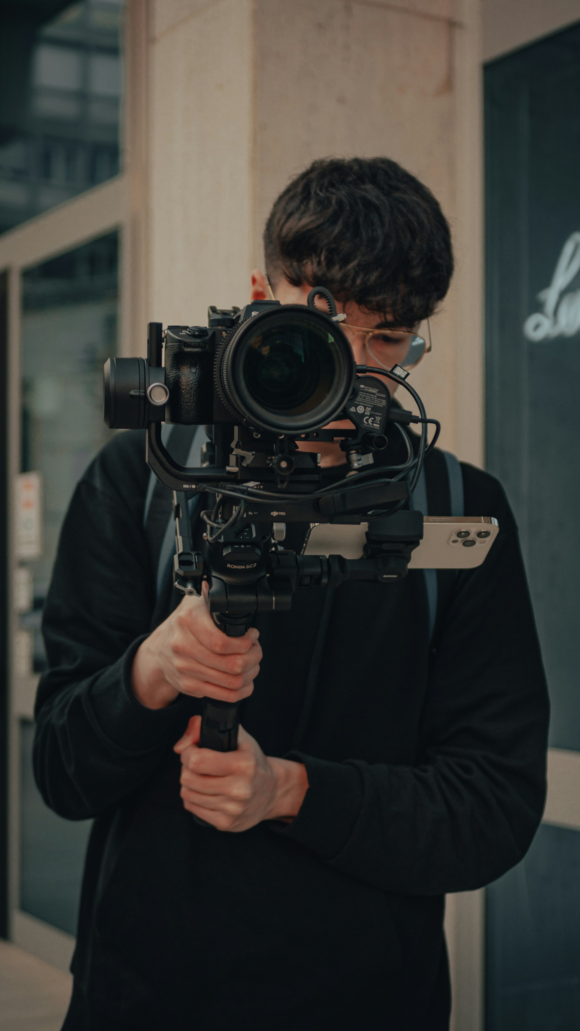 a man wearing a black coat and holding a large black camera