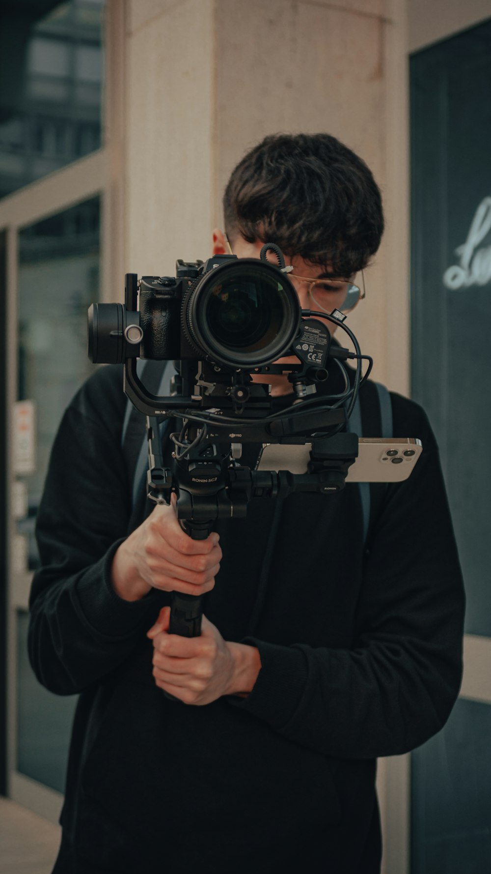 a man wearing a black coat and holding a large black camera