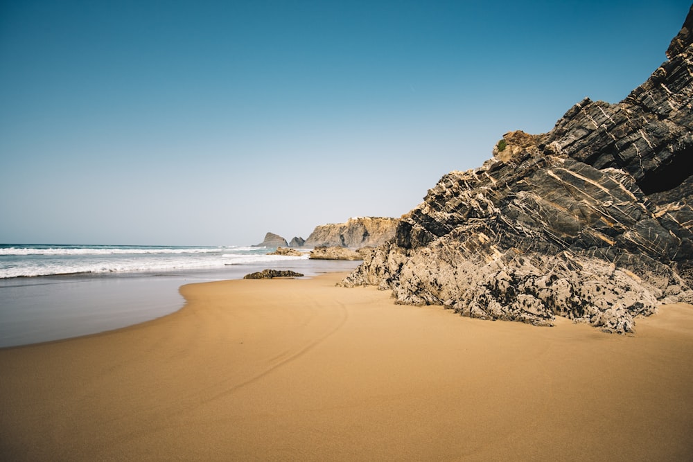 a sandy beach with a rocky cliff